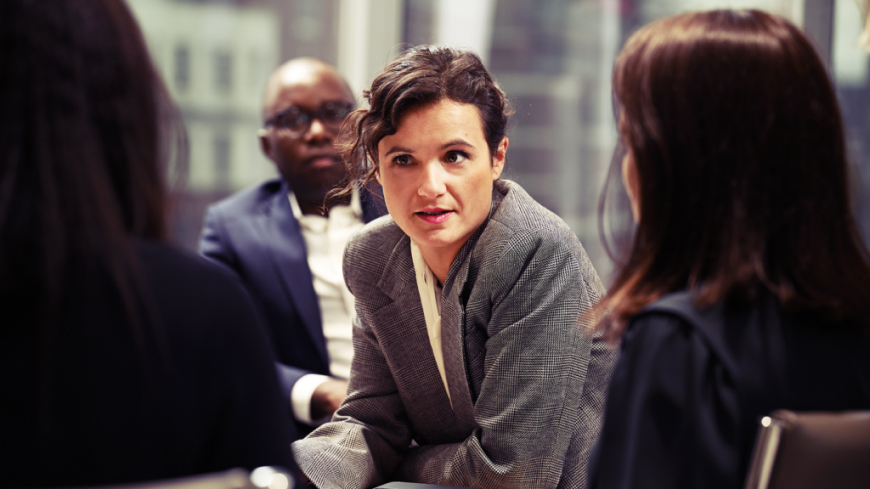 Lady in a meeting an office environment with two other women and a man around her